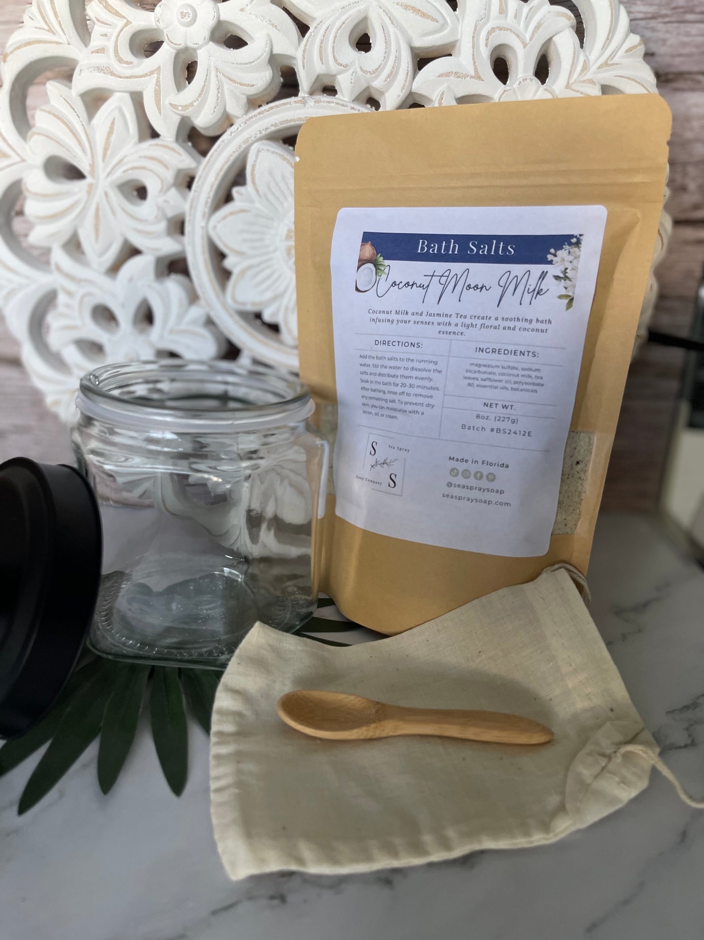 Bath salts package with a spoon and jar on a decorative surface