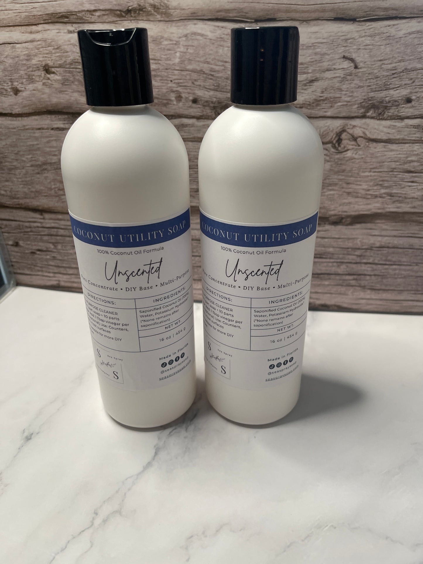 Two bottles of 'Unscented' product on a wooden surface with a white towel underneath.