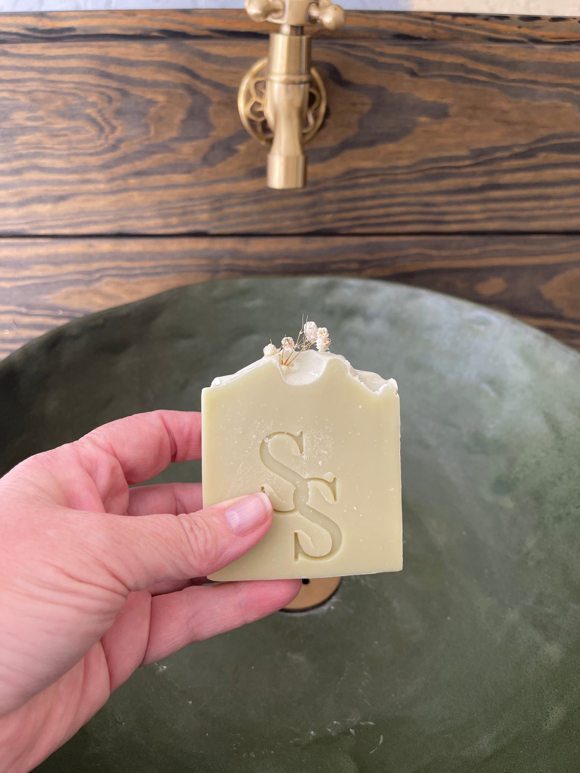 Hand holding a bar of soap with a logo next to a green door