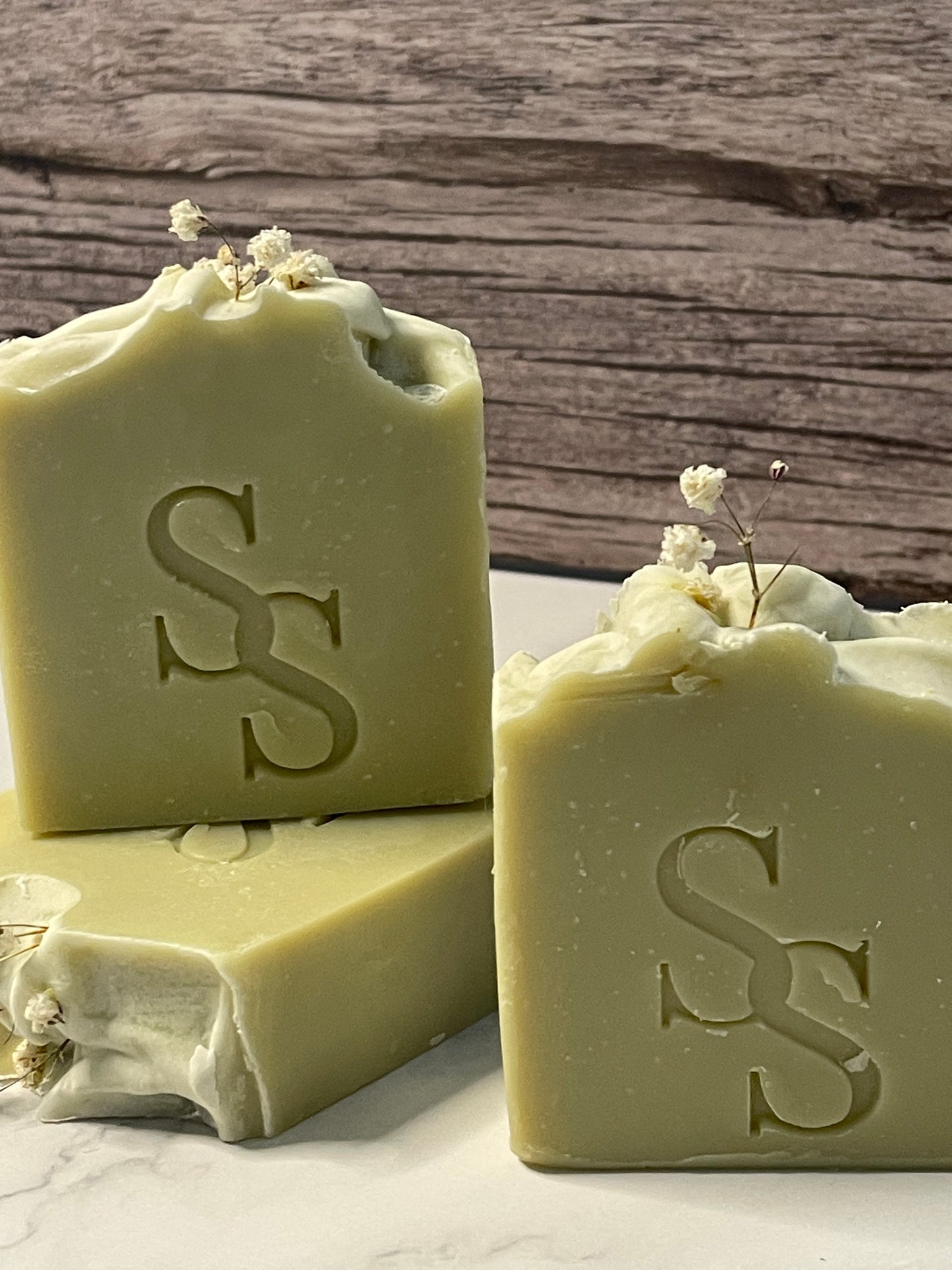 Two bars of soap with a logo on a wooden surface