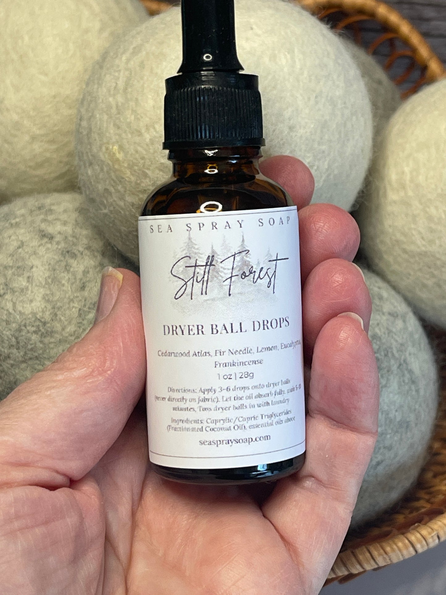 Hand holding a bottle labeled 'Sea Spray Soap' with dryer balls in the background