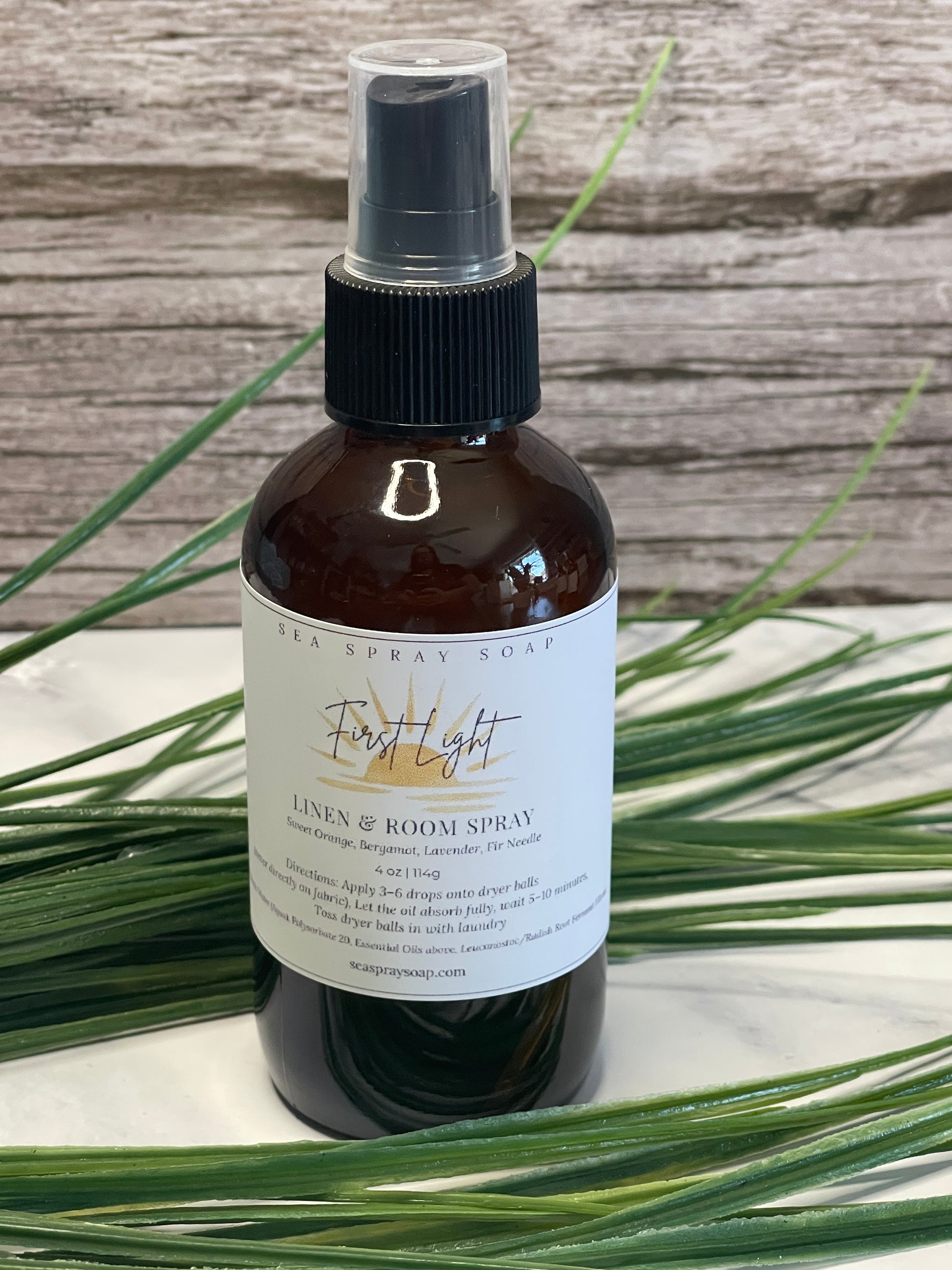 Bottle of room spray with a label on a wooden surface with plants in the background