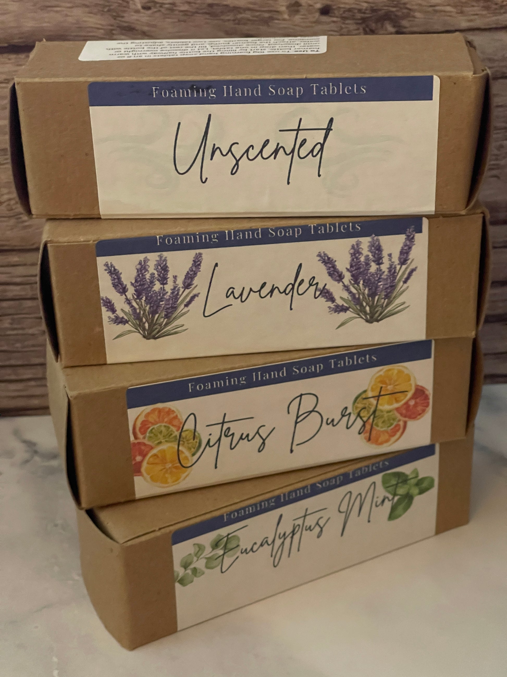 Three boxes of Unsentimental soap with different scents on a wooden surface.