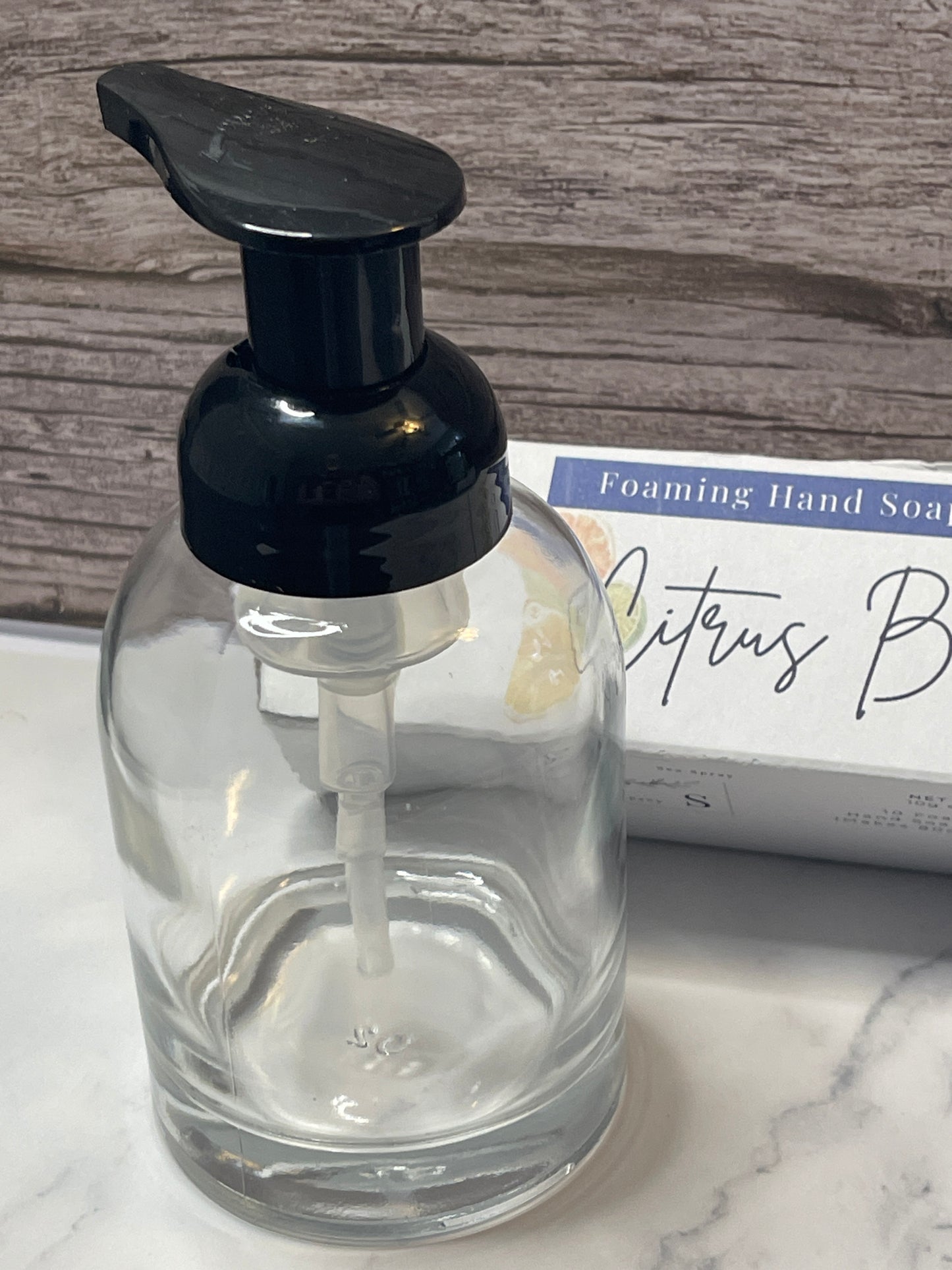 Clear glass bottle with black pump dispenser on a marble surface