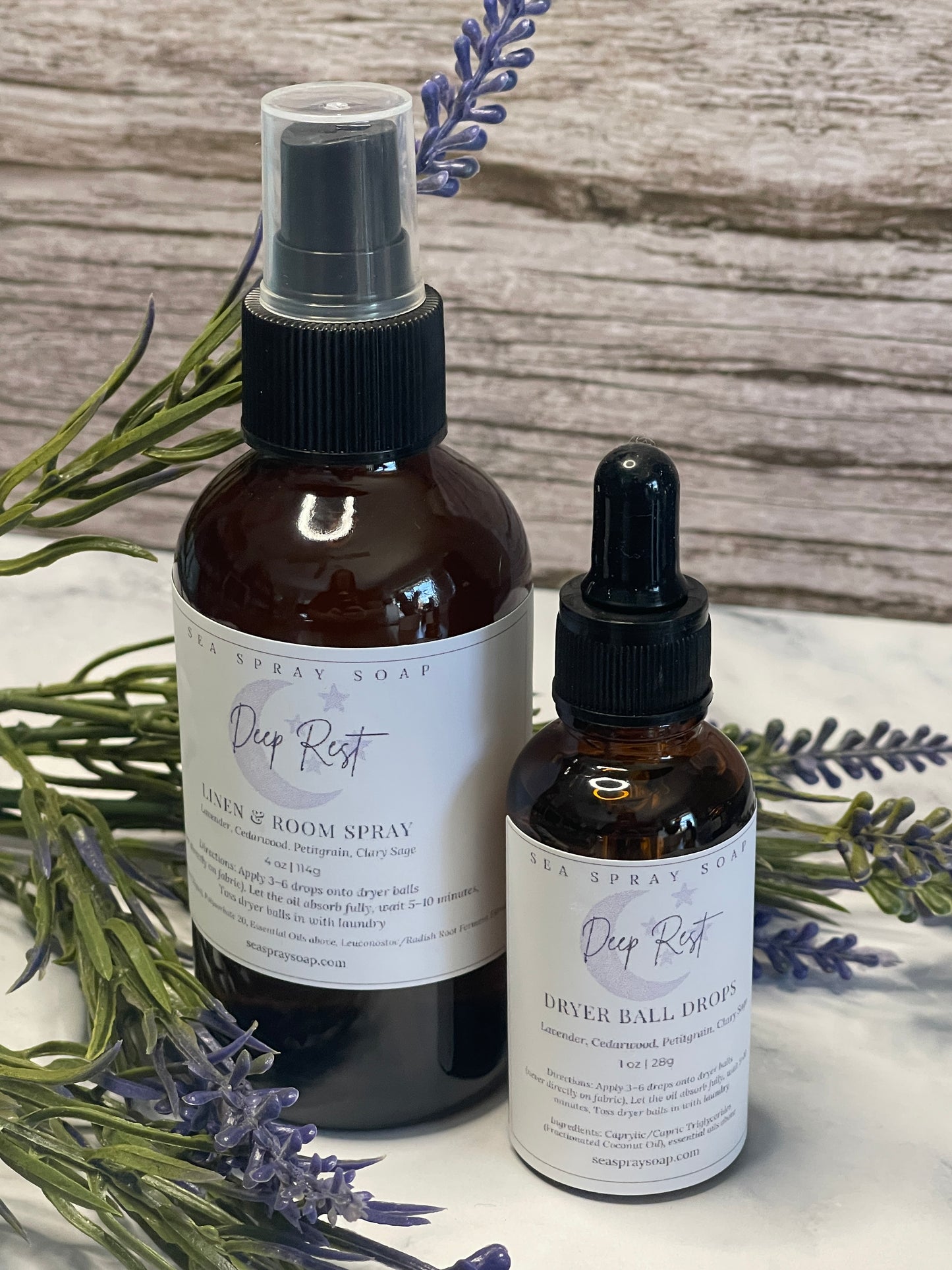 Two bottles of Deep Rest Aromatherapy products on a wooden surface with lavender flowers.