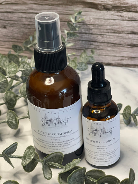 Two brown bottles with black sprayer nozzles on a wooden surface with green leaves.