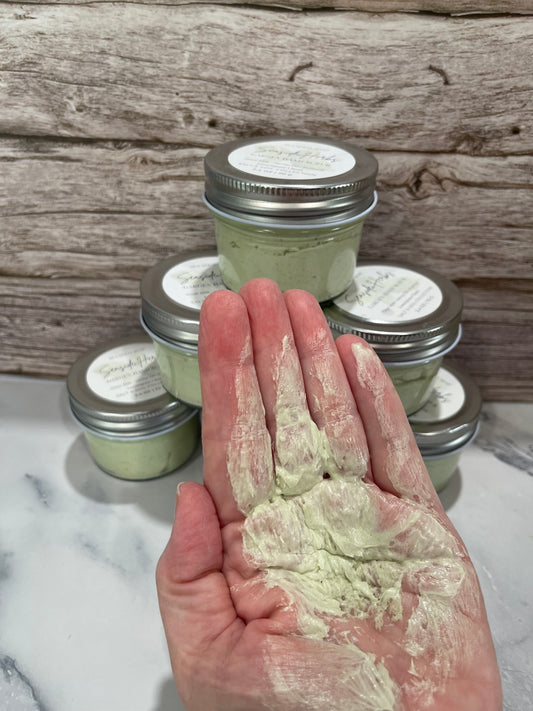 Hand holding a jar of green powder next to jars labeled 'Baking Soda' and 'Cornstarch' on a wooden surface.