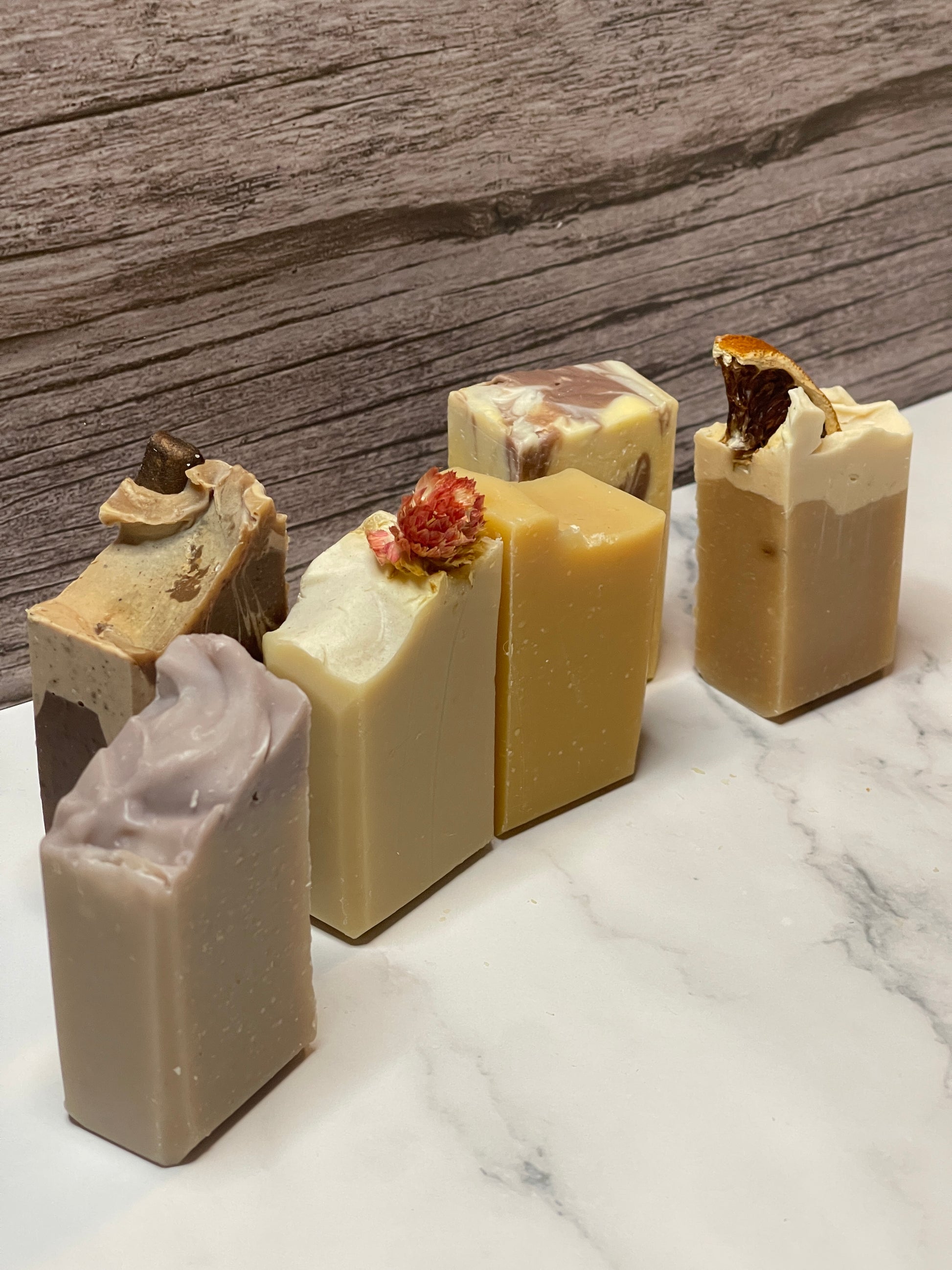 six bars of soap with visible textures on a marble surface