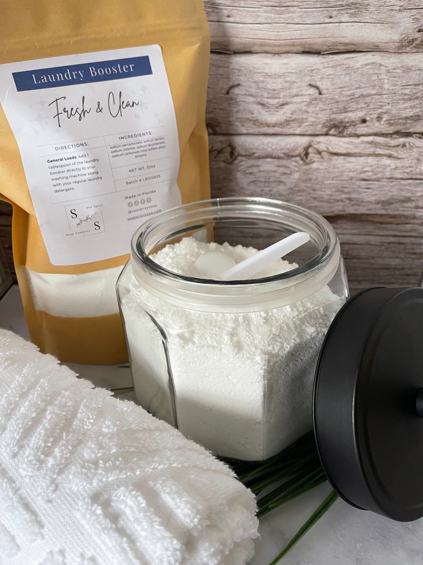Jar of laundry booster powder next to a package labeled 'Frisch & Clean' on a wooden surface.