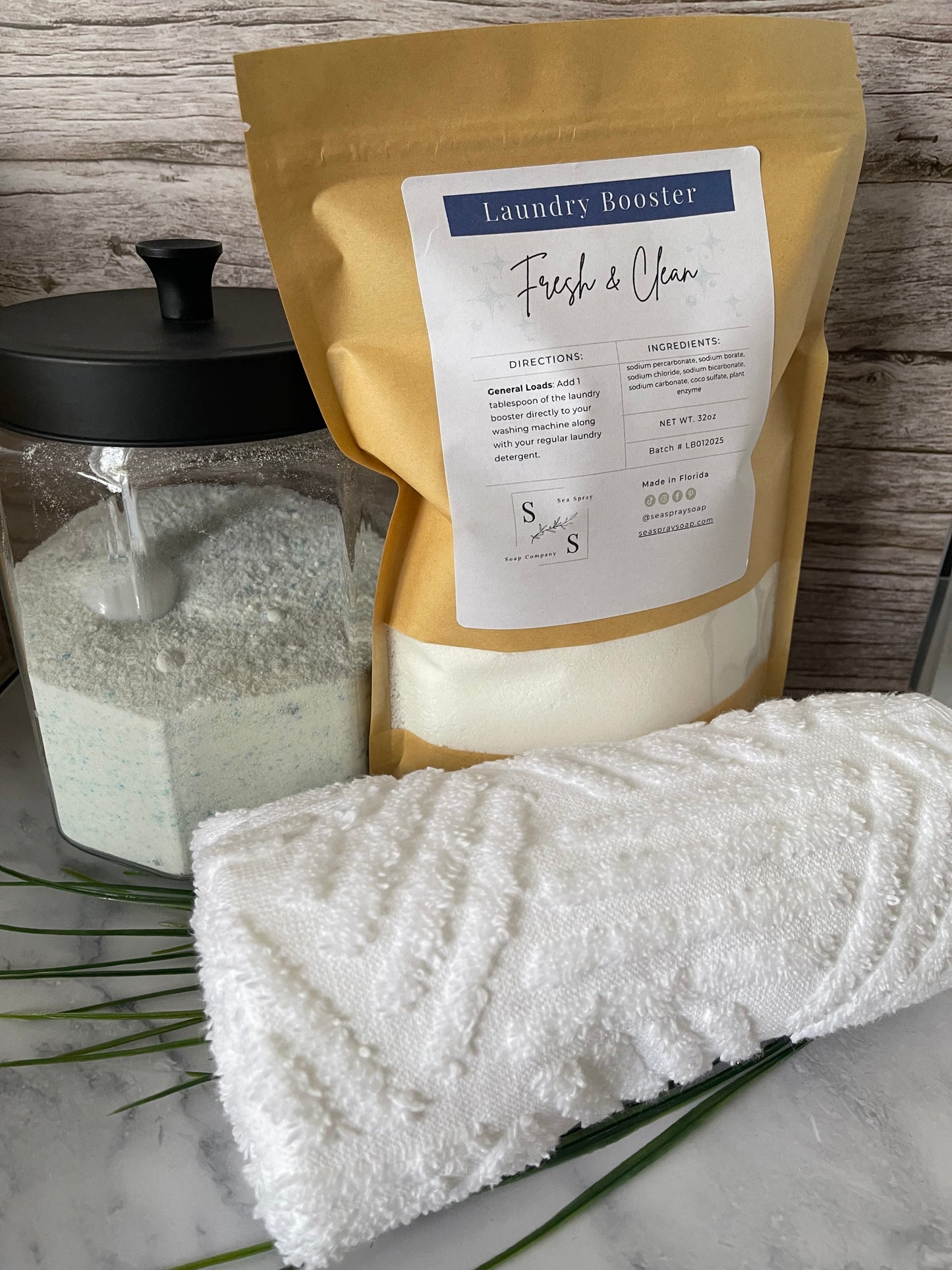 Laundry booster packet and white towel on a textured surface