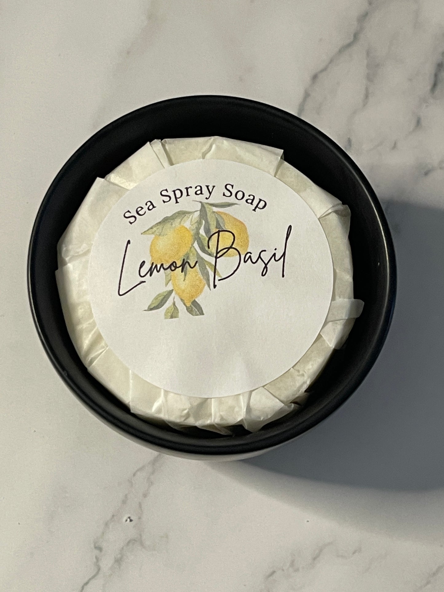 Sea spray soap in a black container with a decorative label on a marble surface