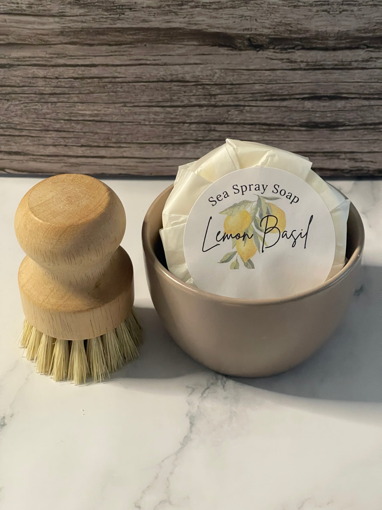 Sea spray soap in a cylindrical container with a wooden brush on a marble surface.