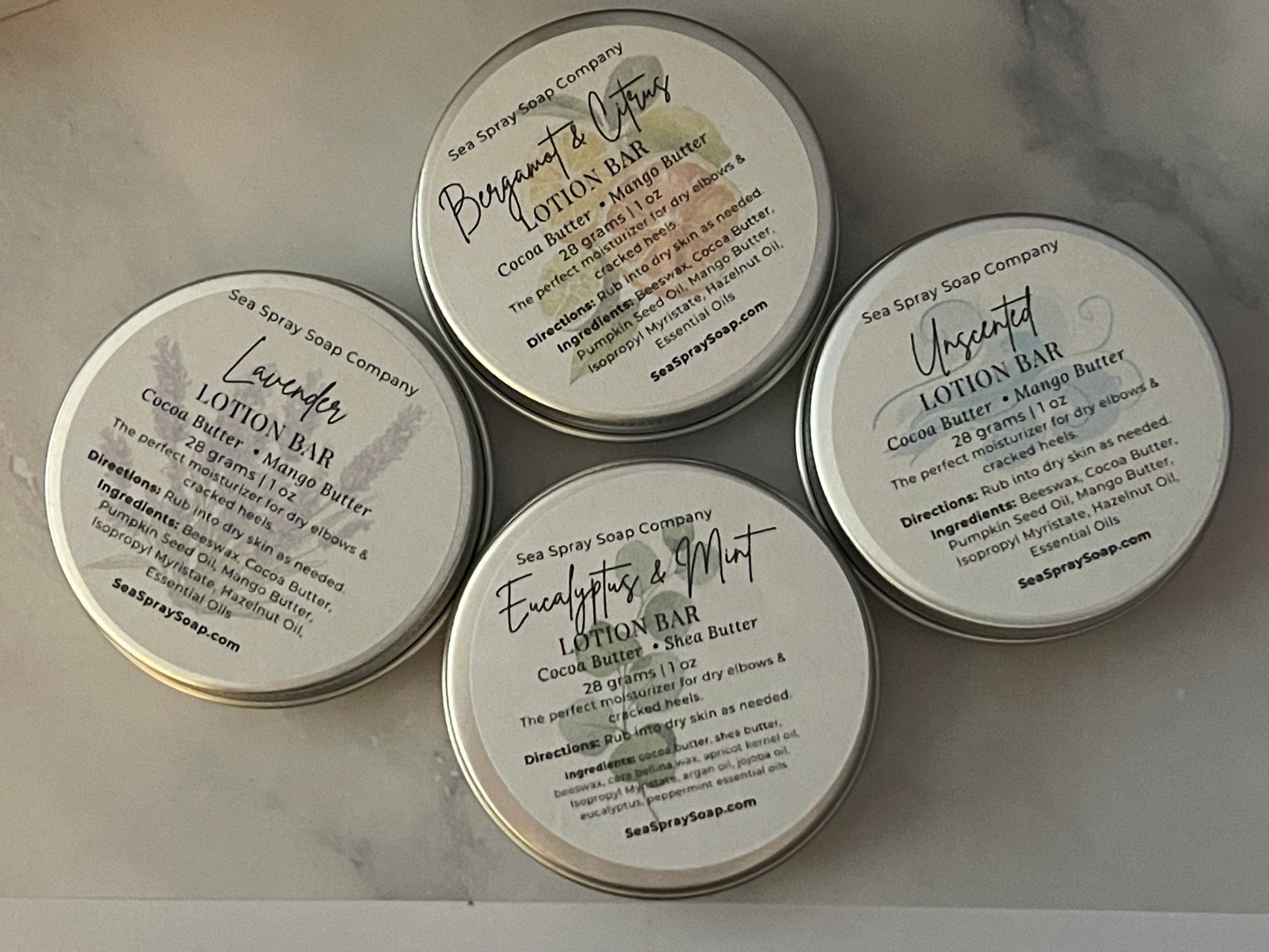 Five containers of Sea Spray Soap Company lotion bars on a marble surface.
