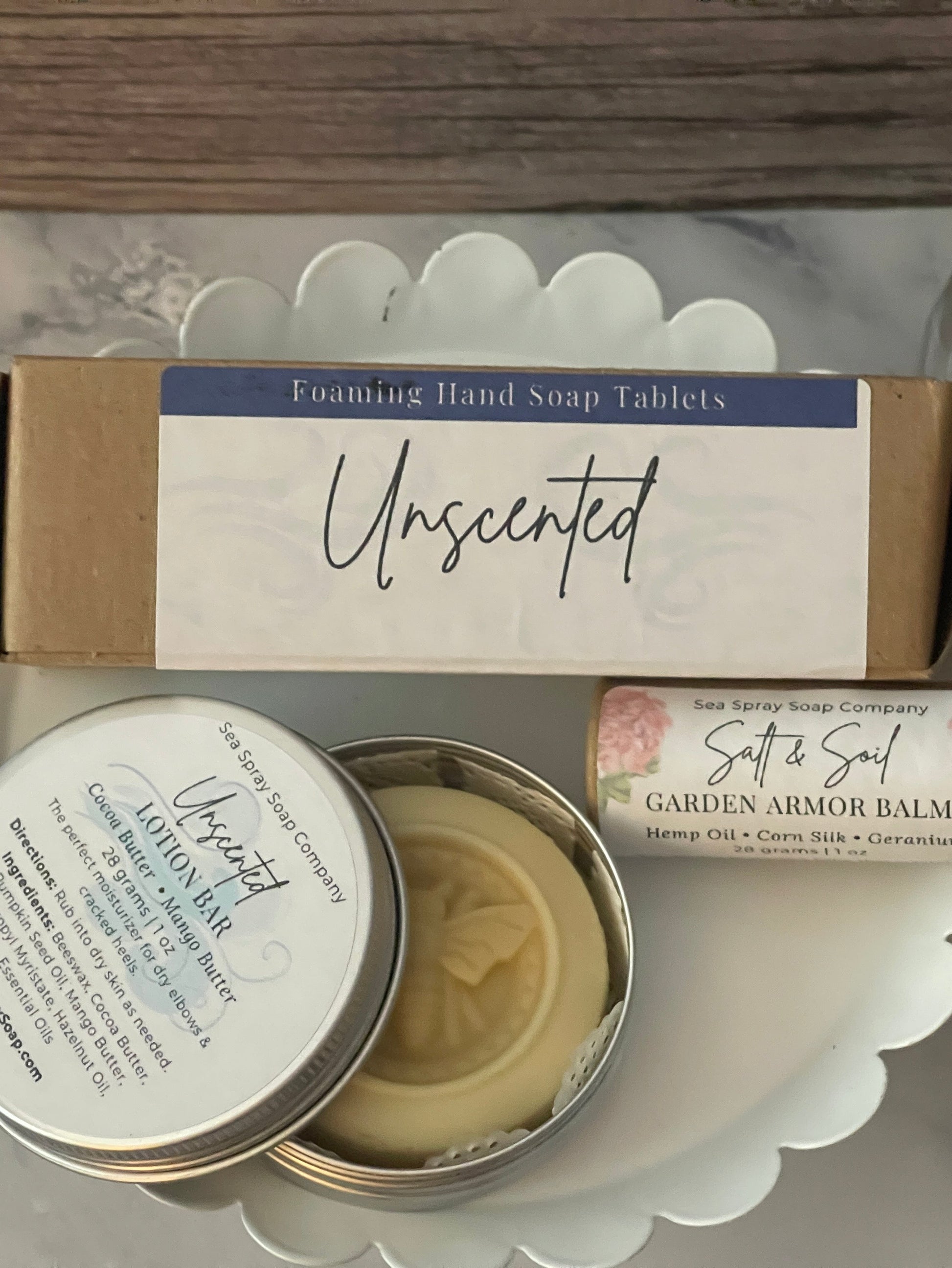 Collection of skincare and wellness products including a tin, soap tablets, and balm on a white surface.