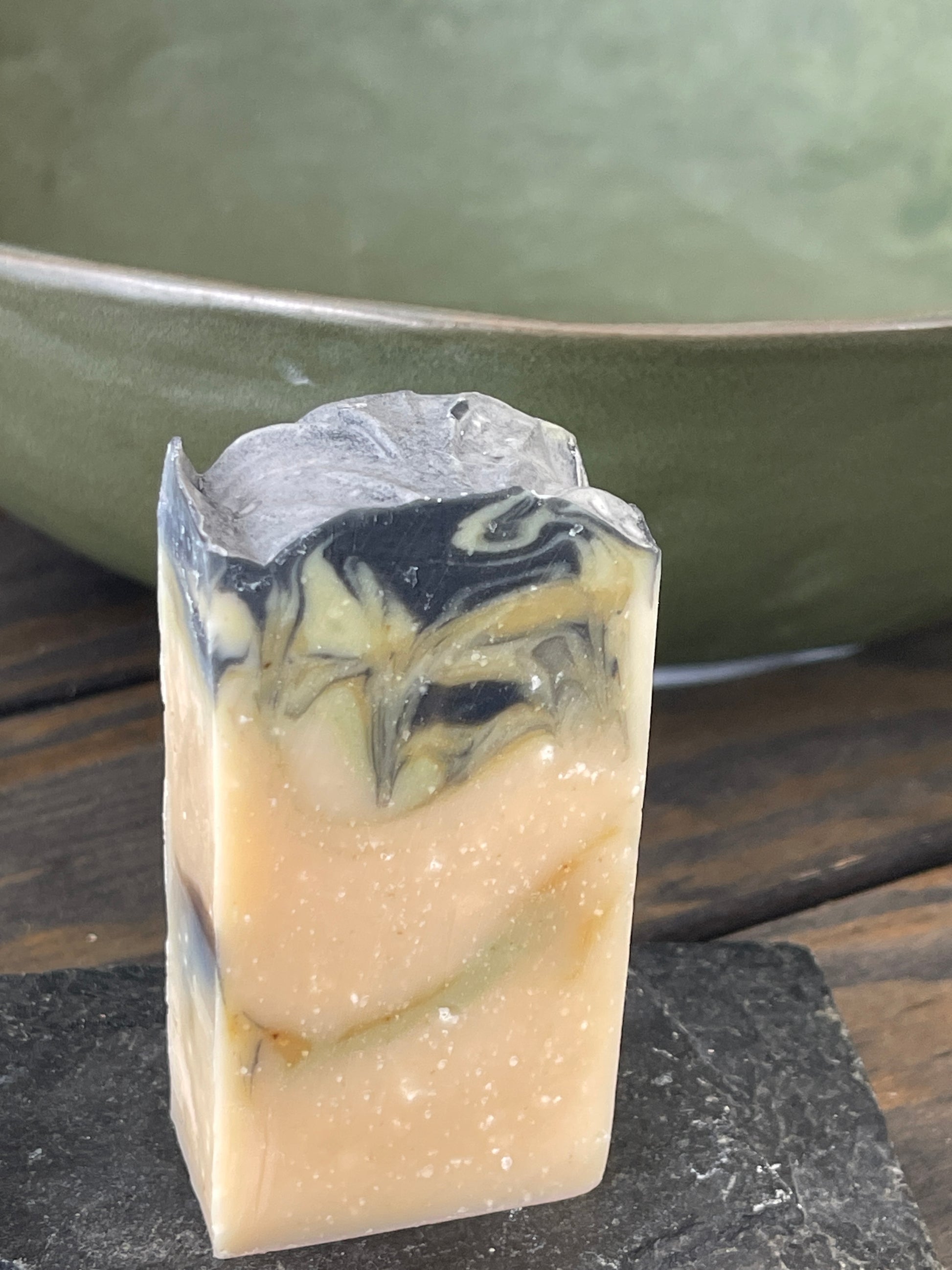 Bar of soap with black and green swirls on a wooden surface