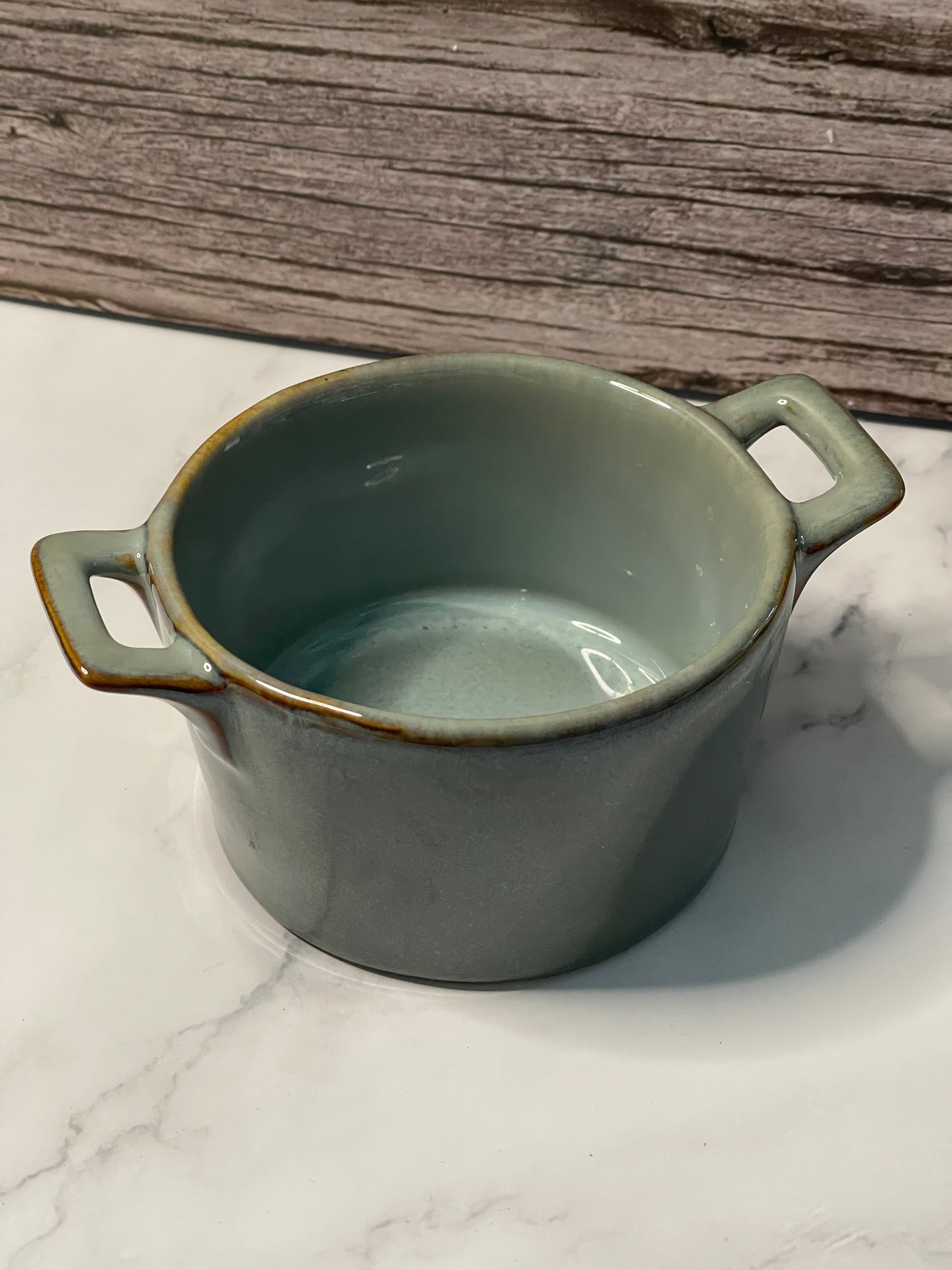 Green ceramic mug with handles on a marble surface