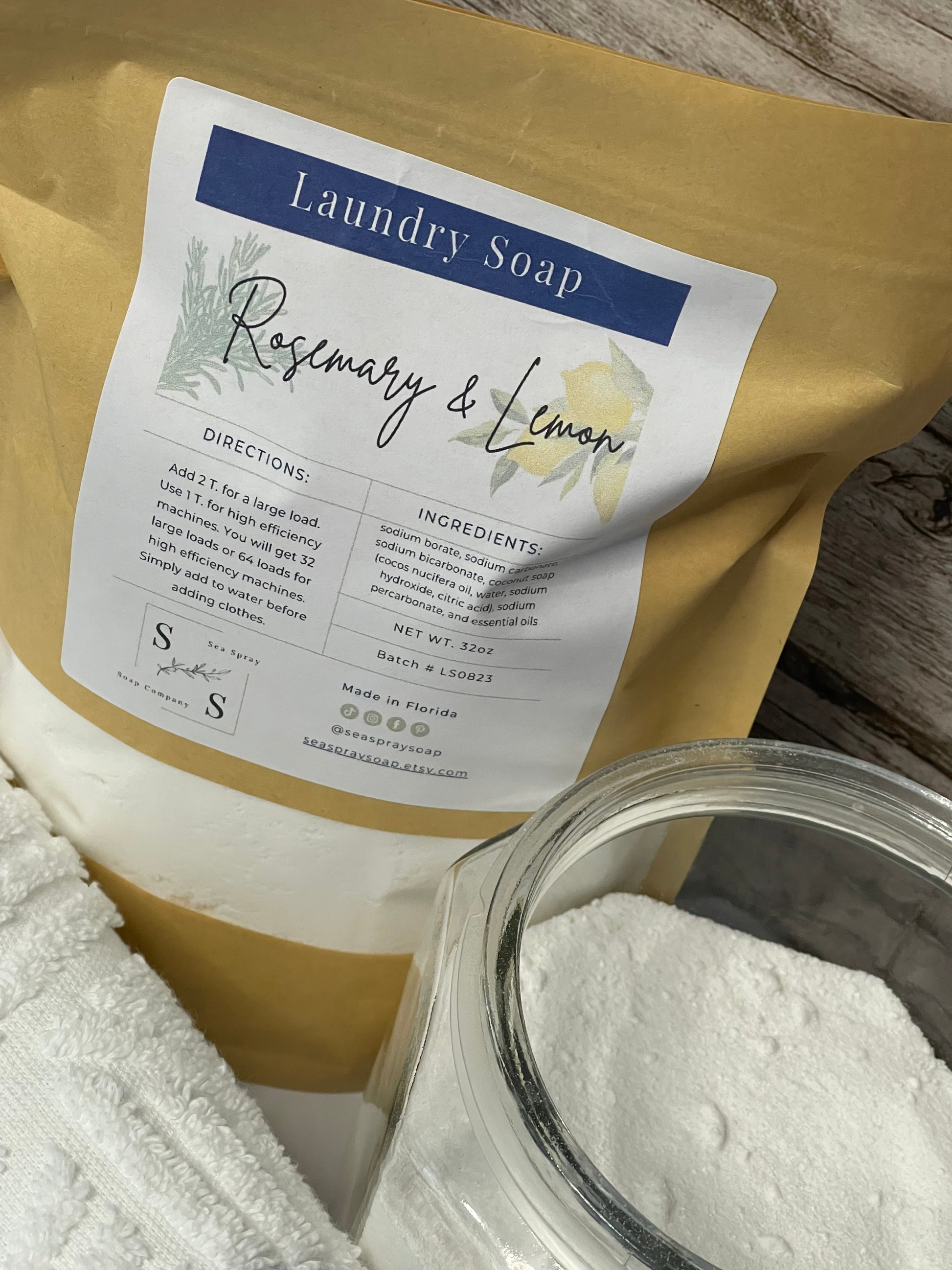 Laundry soap package with a label and a glass container of detergent on a wooden surface.