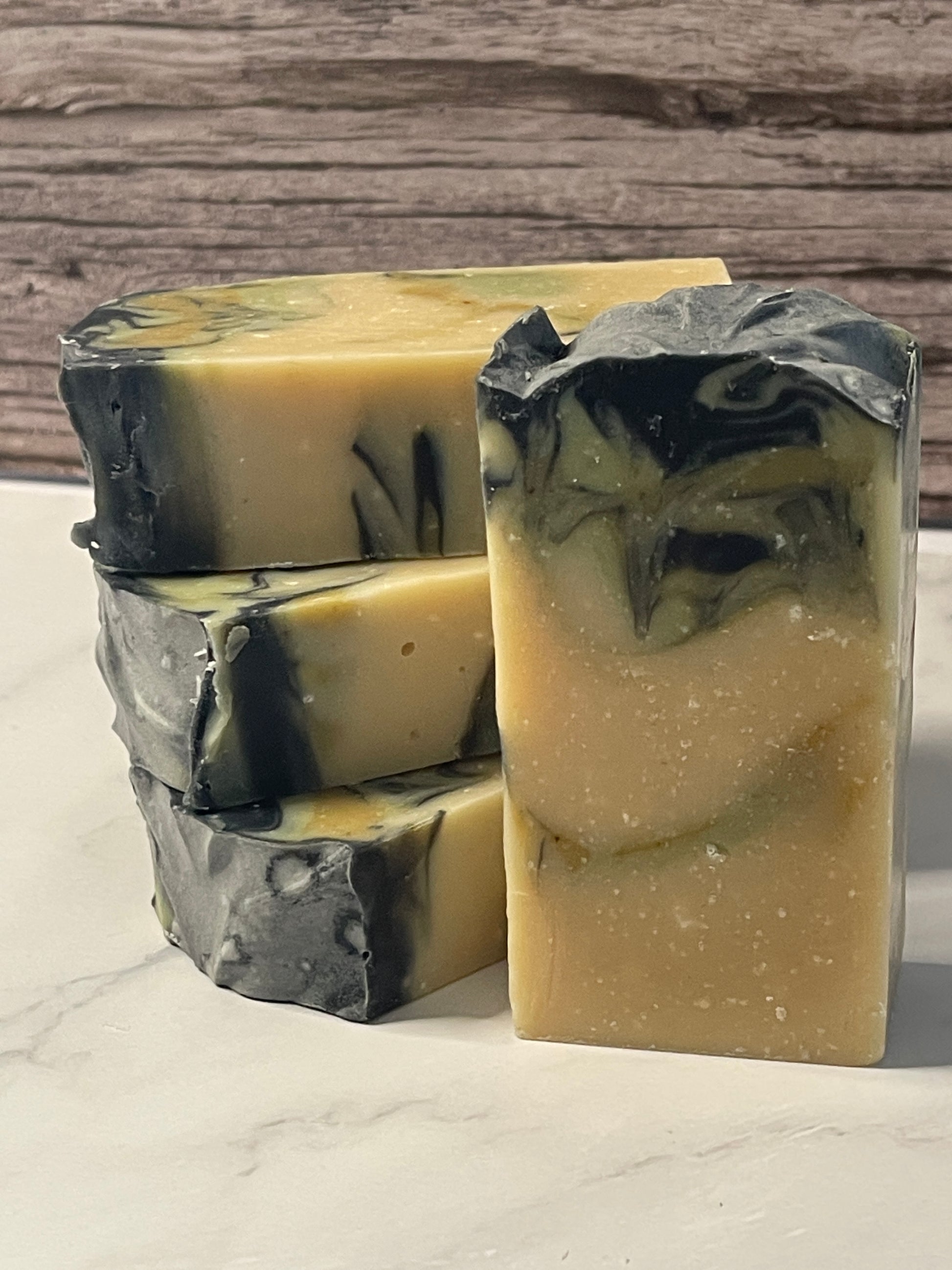 Two bars of soap with black and beige swirls on a wooden surface.