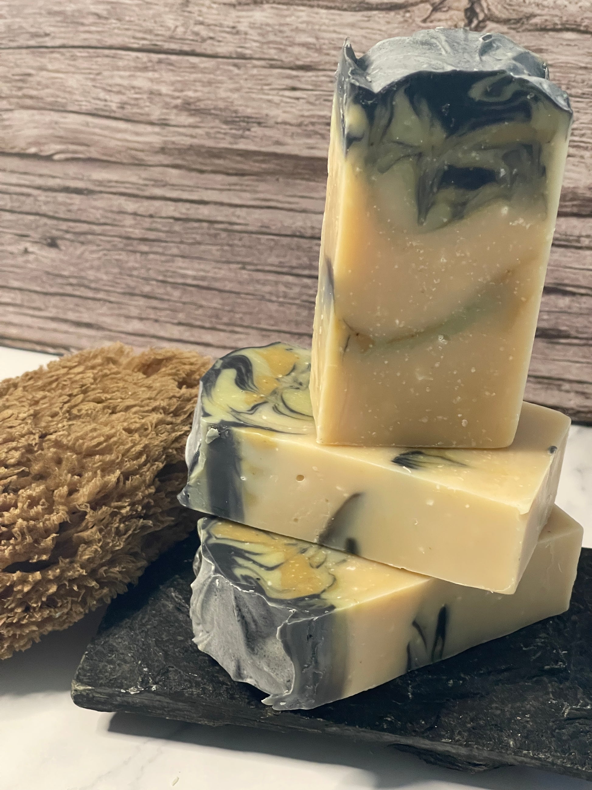 Three bars of soap with a marbled pattern on a wooden surface