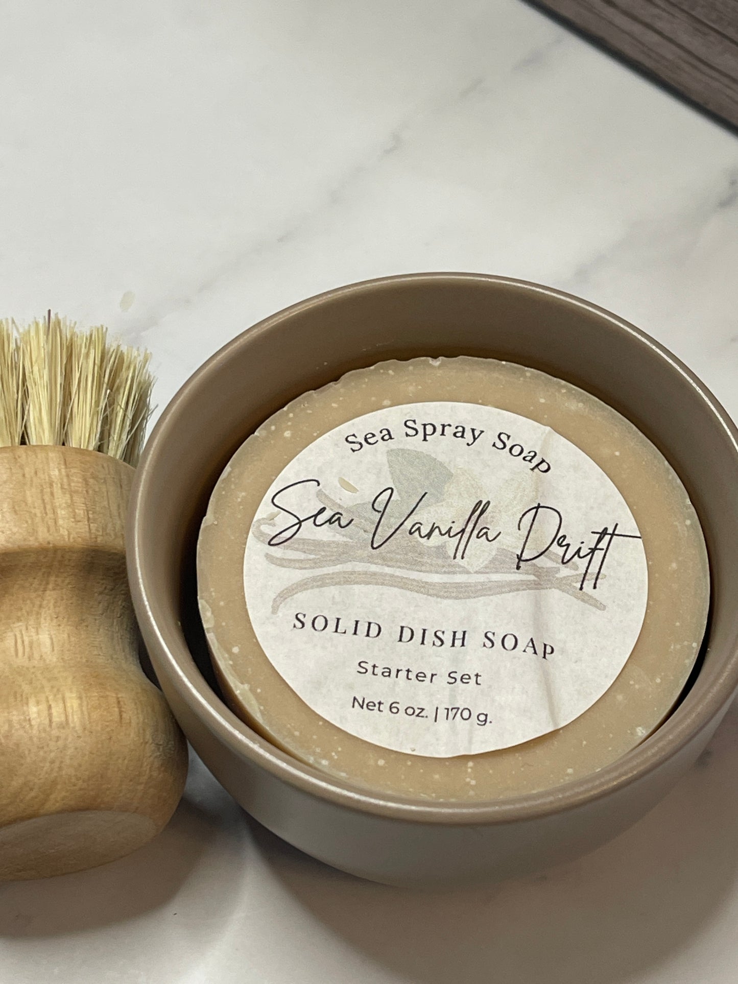 Solid dish soap in a container with a label on a marble surface