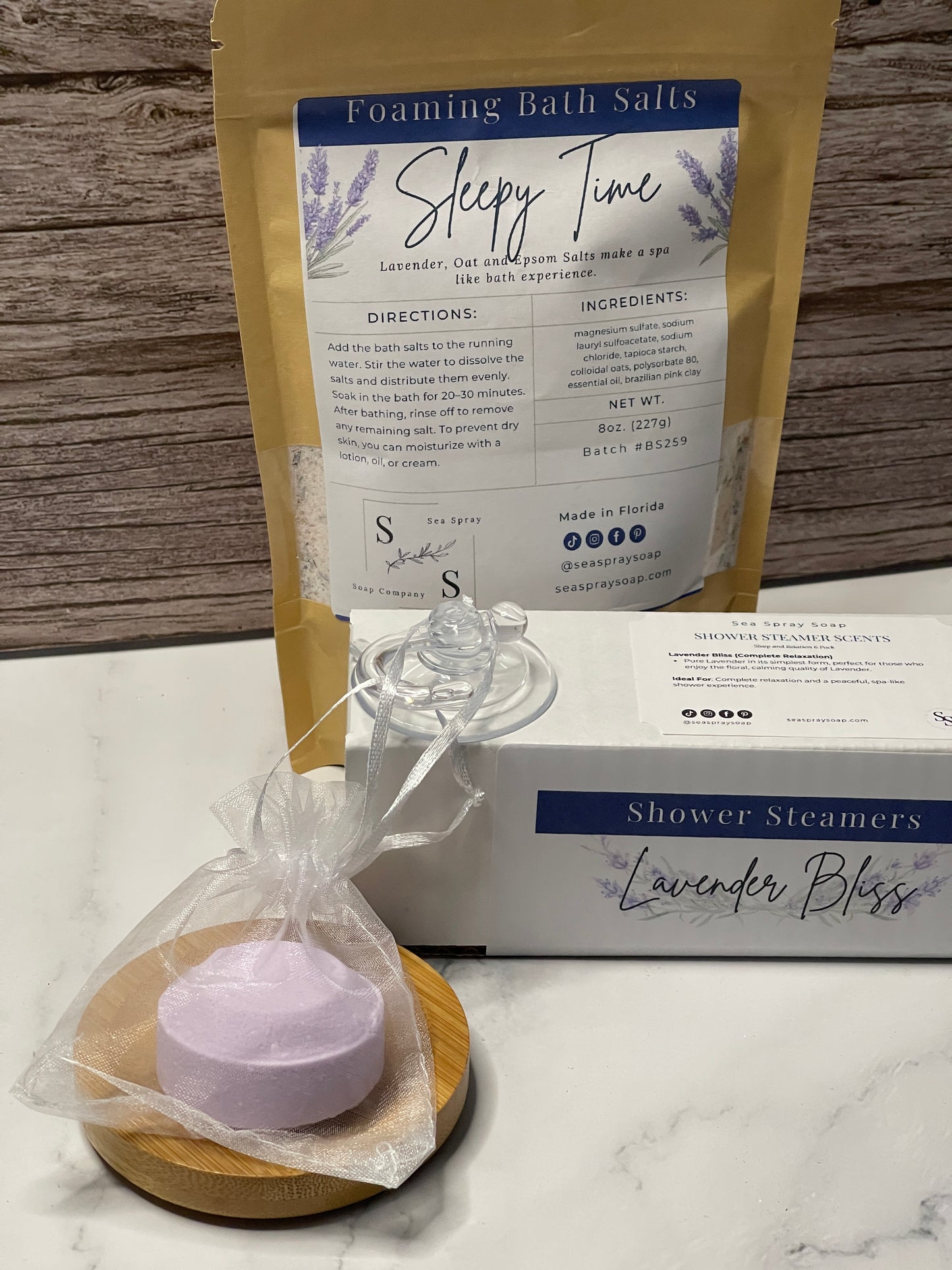 Lavender-themed product set including bath salts, shower steamers on a marble surface.