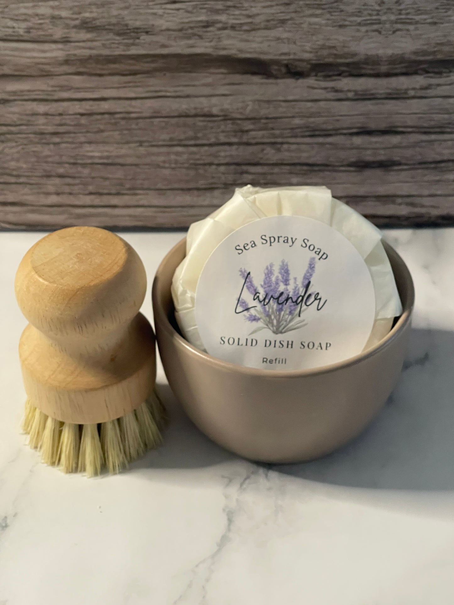 Solid dish soap in a container with a brush on a marble surface