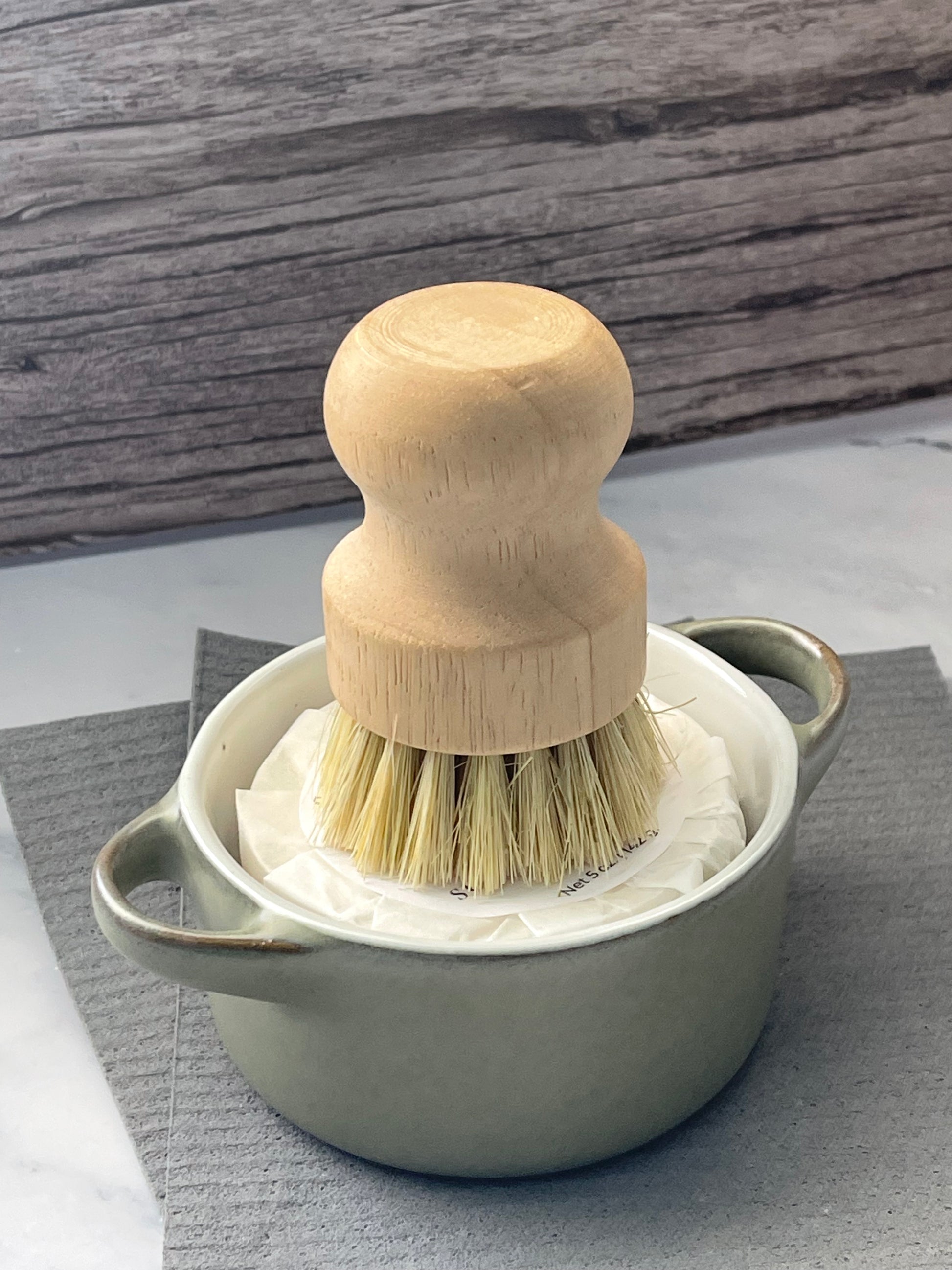 Dish with solid dish soap in it with a palm brush and Swedish dish cloths