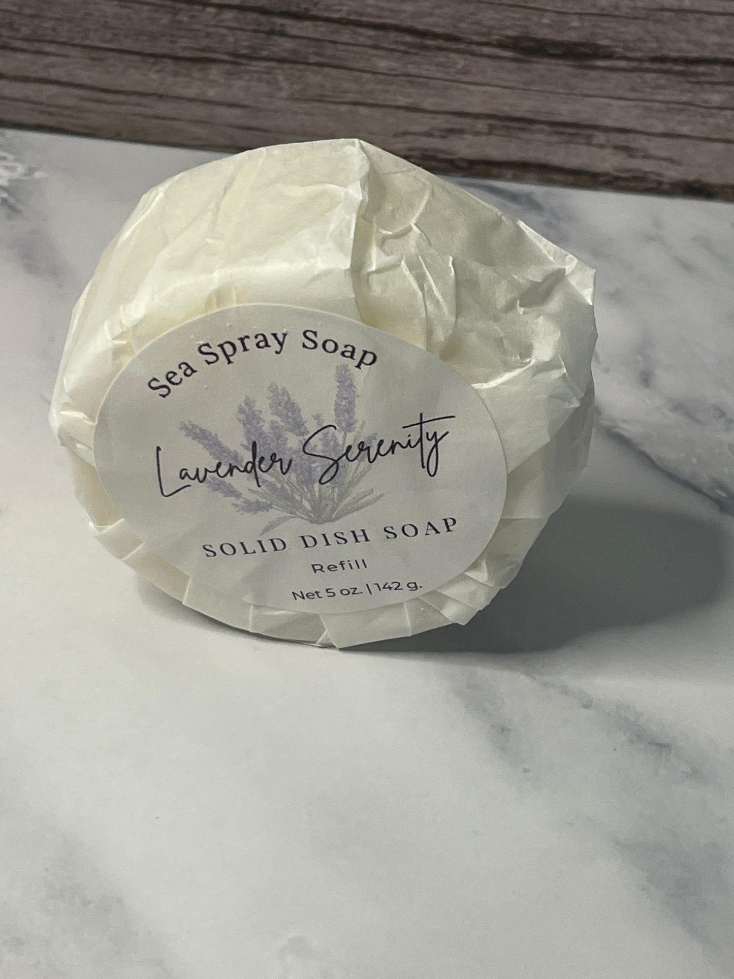Solid dish soap bar with a label on a marble surface