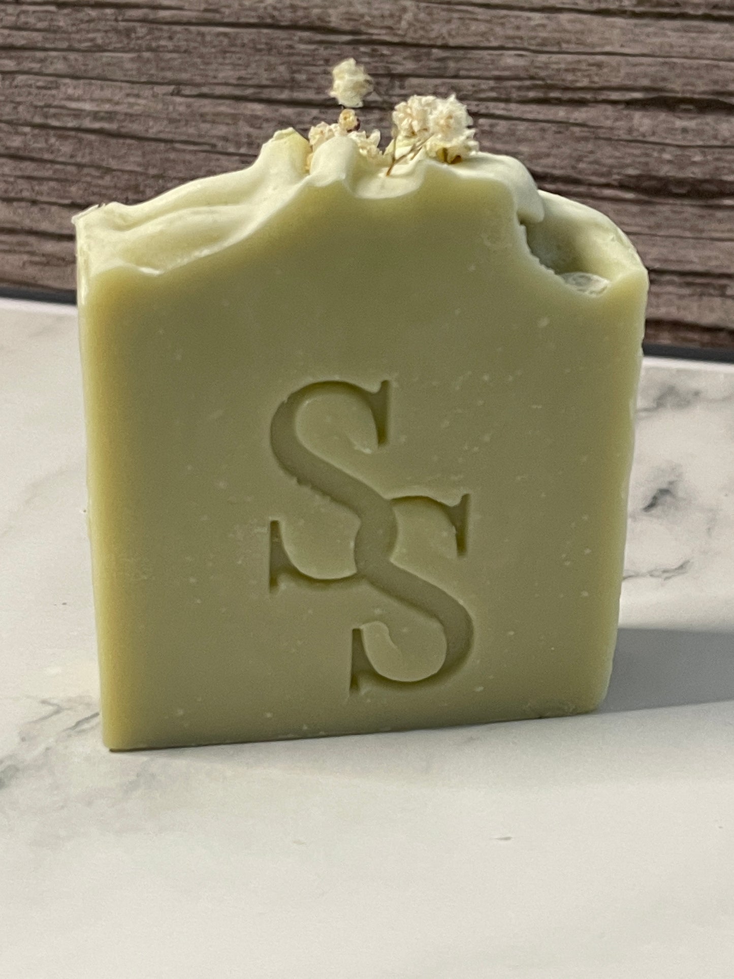 Green bar of soap with a logo on a marble surface