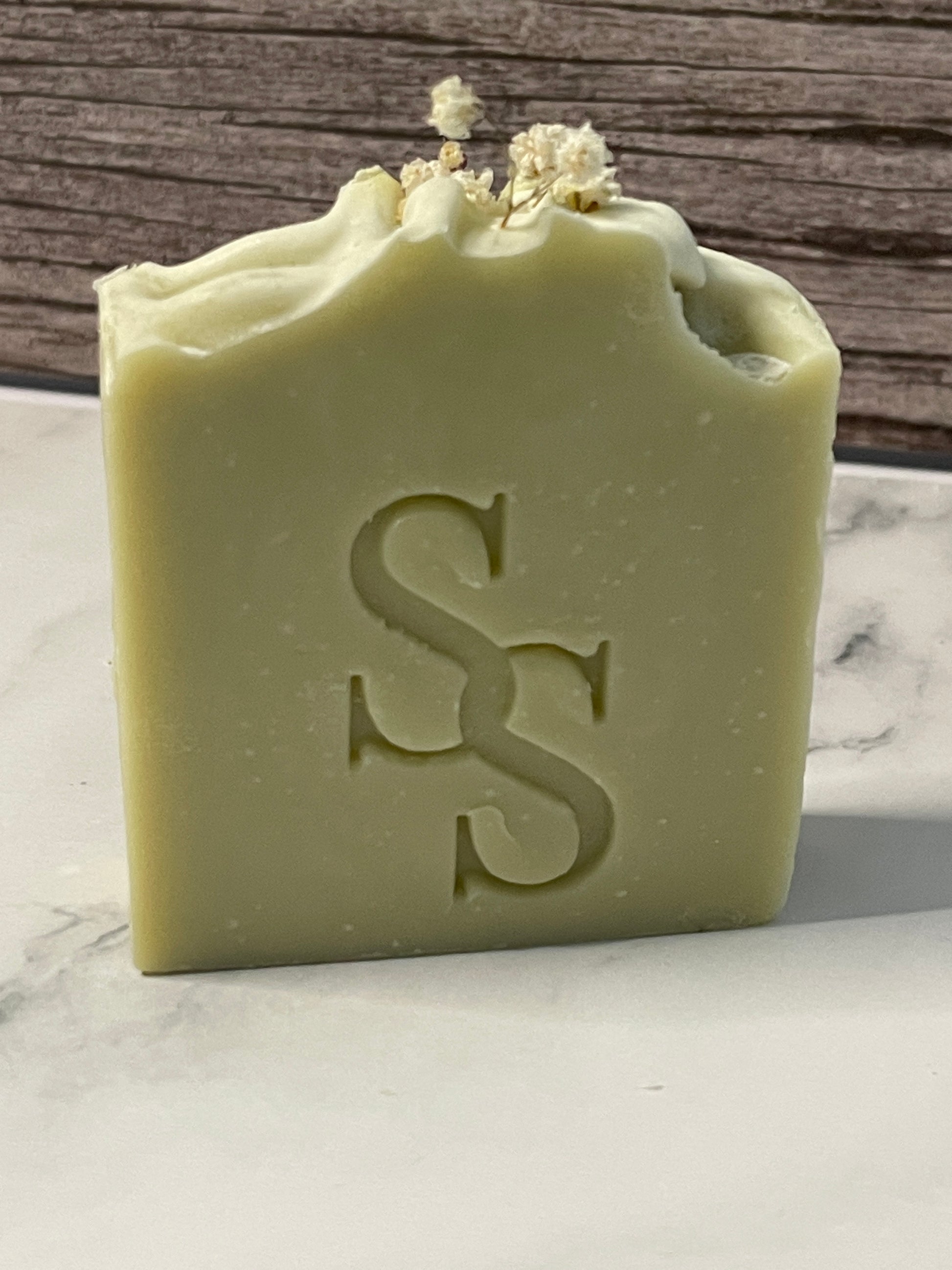 Green bar of soap with a logo on a marble surface