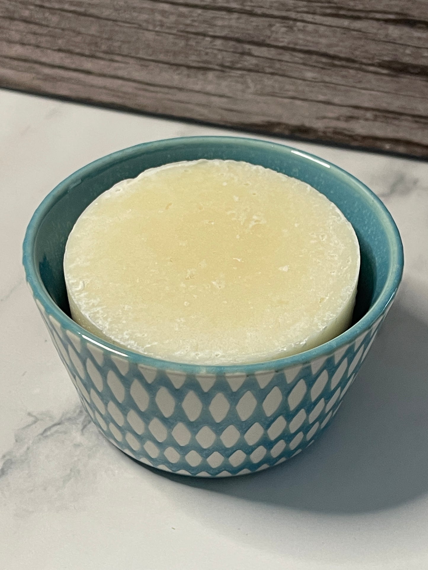 Bar of soap in a blue patterned container on a marble surface
