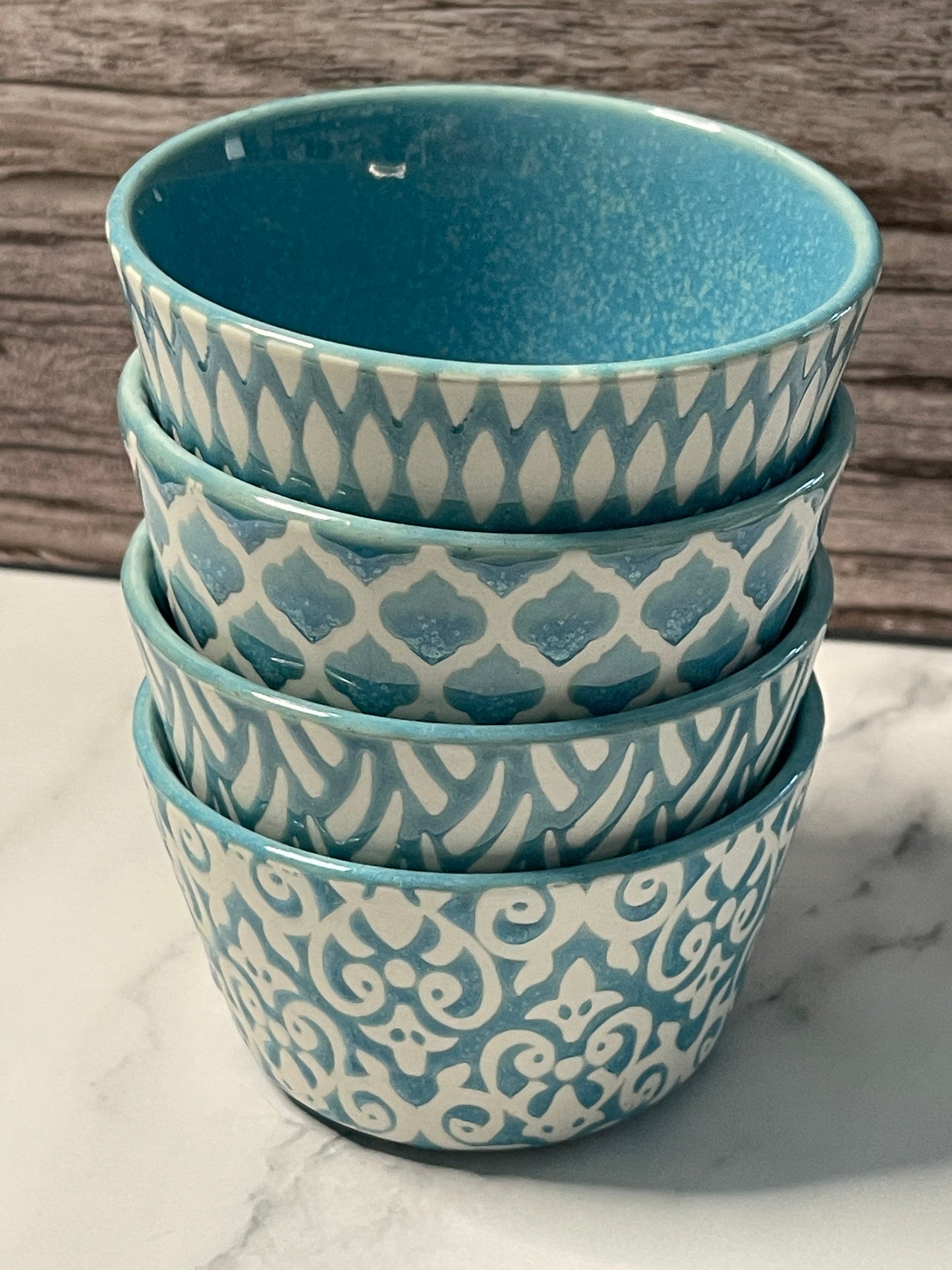 Set of four ceramic bowls with blue and white patterns on a marble surface.