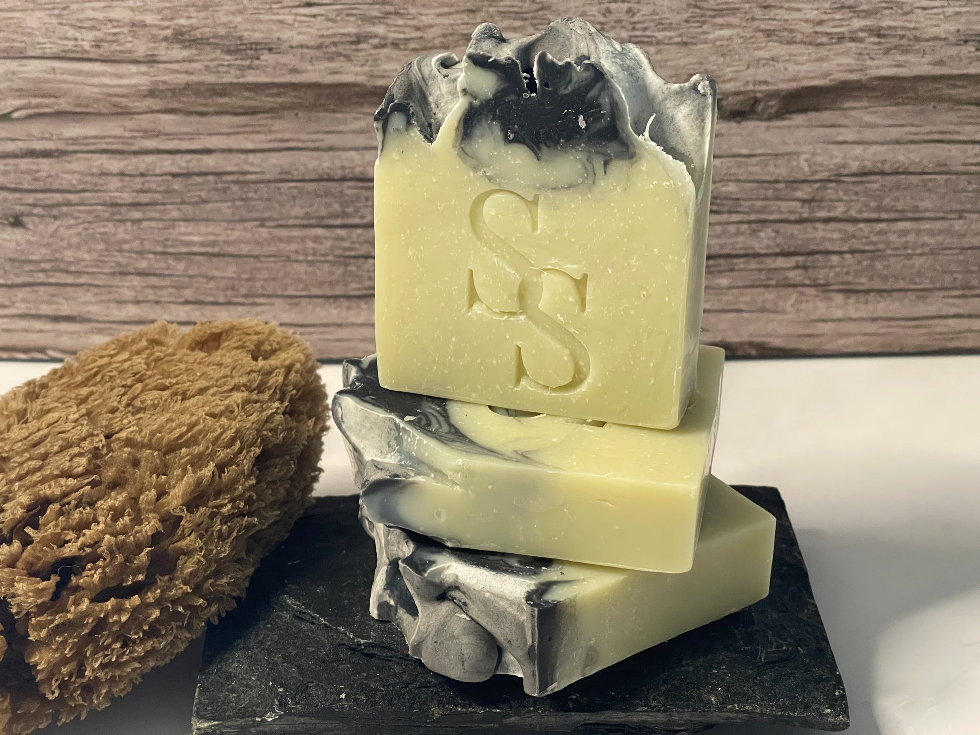 Three bars of soap with a logo on a black stand against a wooden background