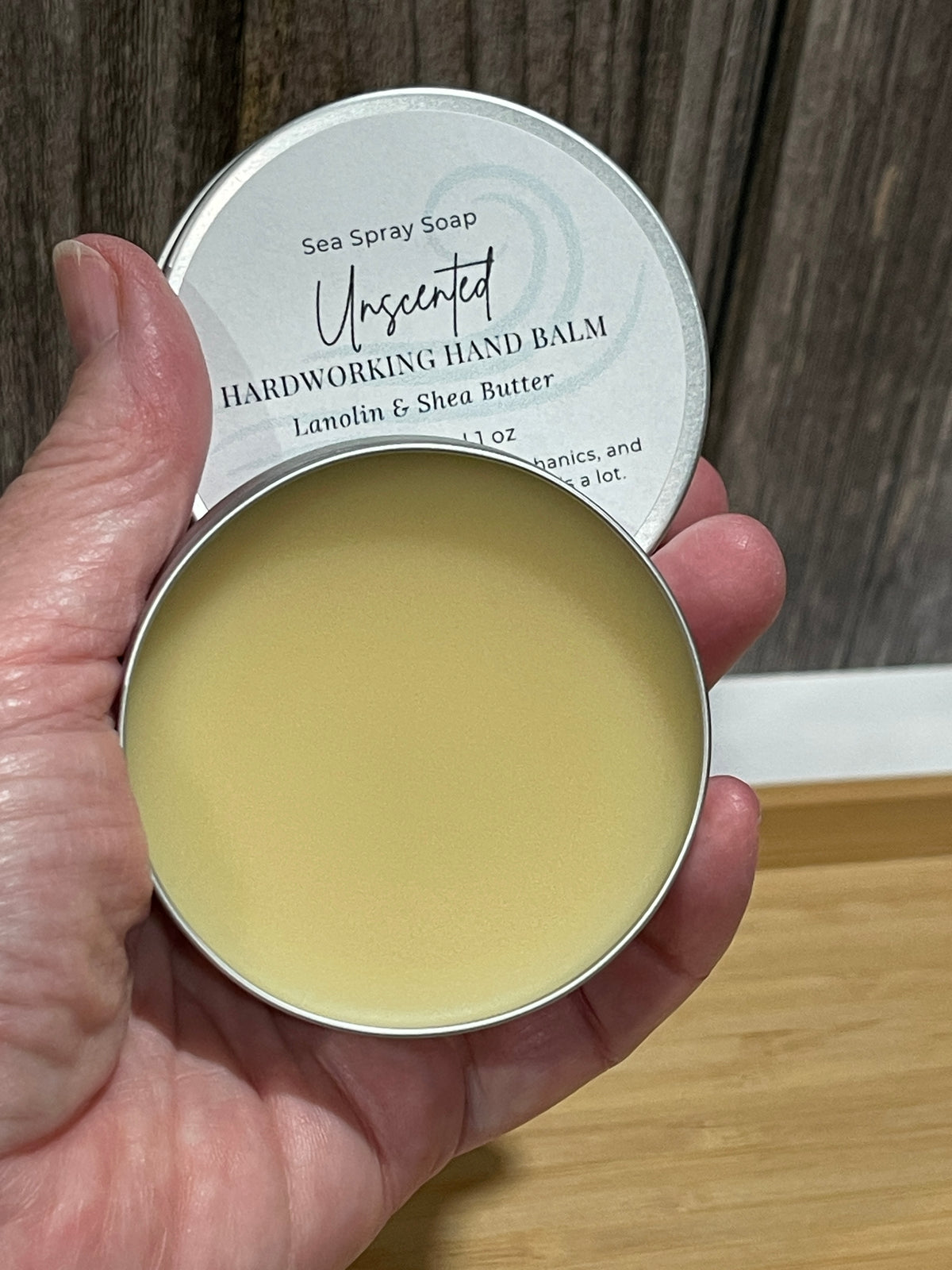 Hand holding unscented 2 oz hardworking hand balm