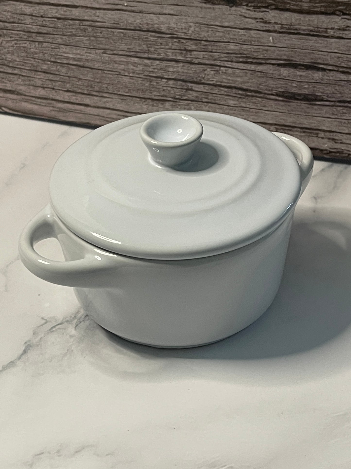 White ceramic pot with lid on a marble surface