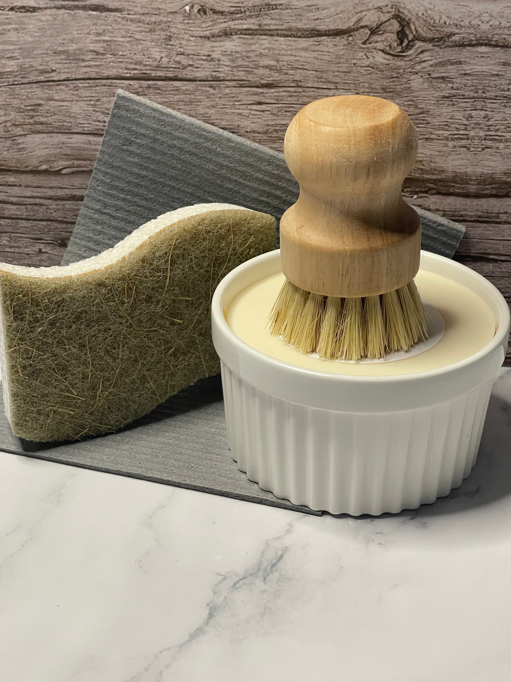 Cleaning brush with wooden handle and white bristles on a marble surface