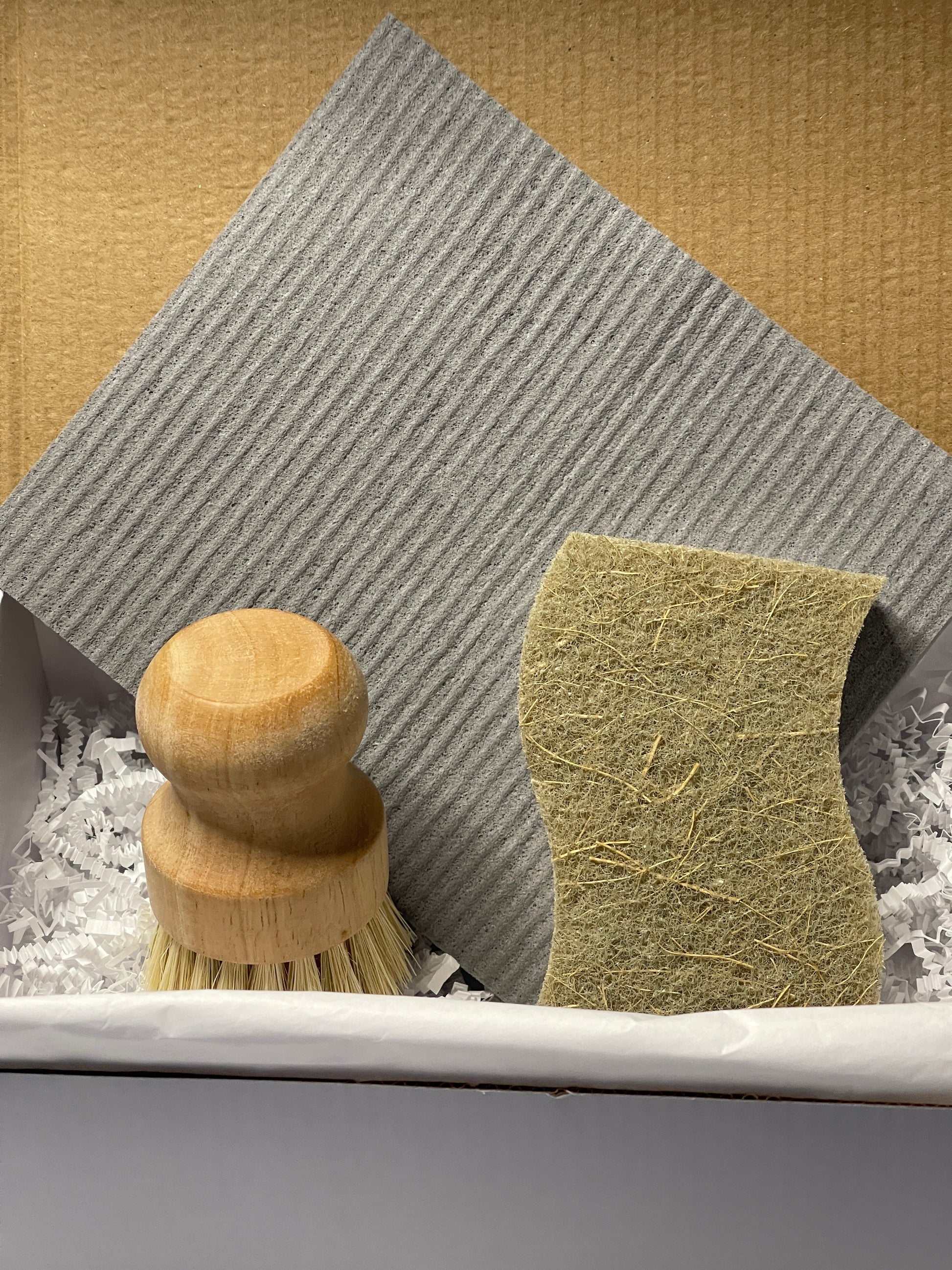 Compostable Sponge, Dish brush and swedish dishcloth set on a textured surface with a neutral background
